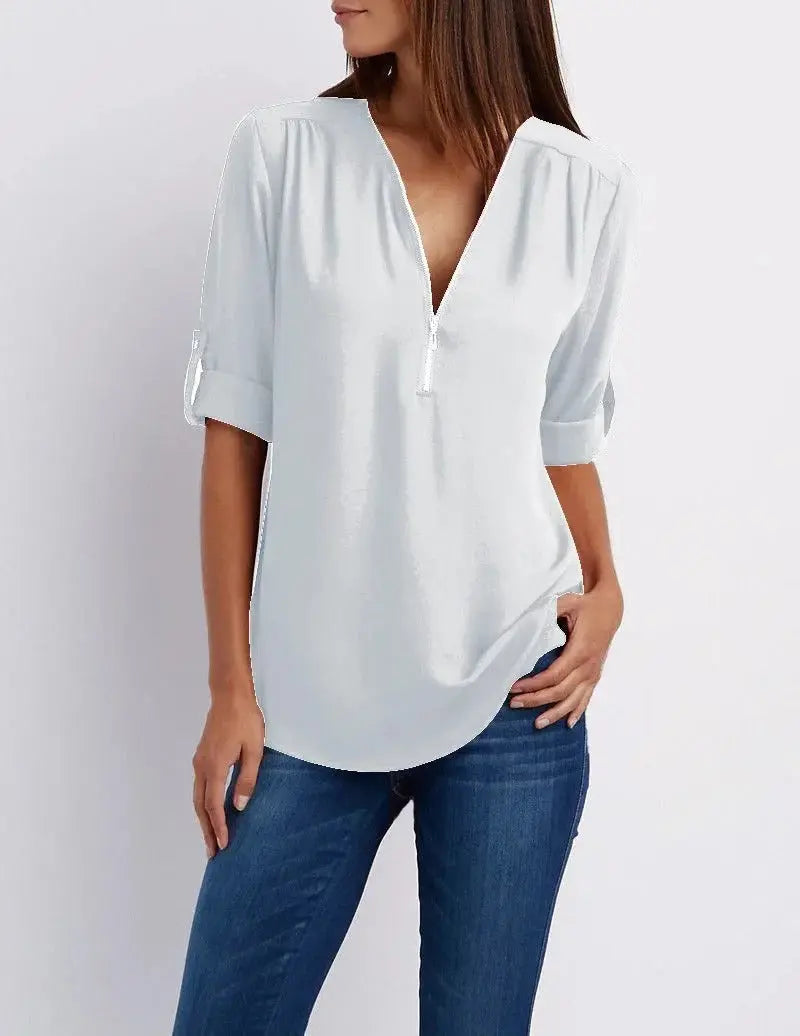 Blusa bianca da donna con scollo a V e maniche a tre quarti, abbinata a jeans blu. Elegante e casual, perfetta per ogni occasione.