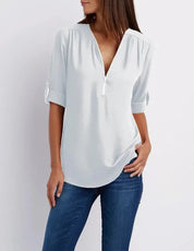 Blusa bianca da donna con scollo a V, maniche a tre quarti, abbinata a jeans blu. Elegante e casual, ideale per moda femminile quotidiana.