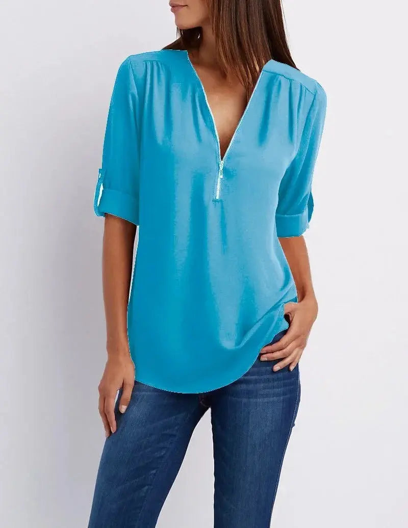 Blusa donna azzurra con scollo a V e maniche a tre quarti, abbinata a jeans. Elegante e casual, ideale per moda femminile primavera-estate.