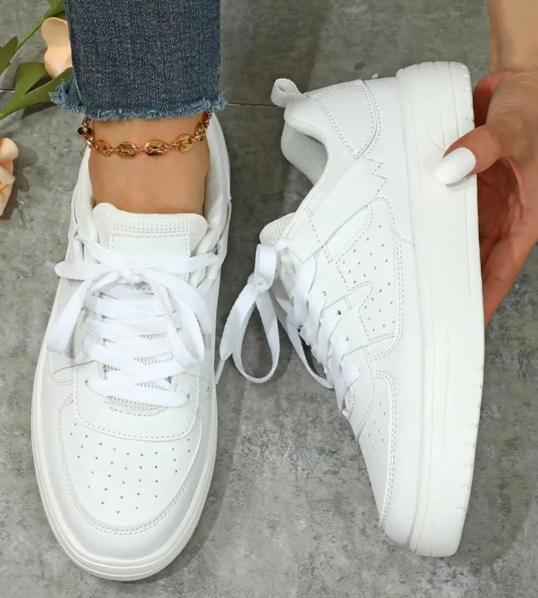 Scarpe da ginnastica bianche da donna, suola spessa, lacci, indossate con jeans. Design moderno, perfette per look casual e sportivi.