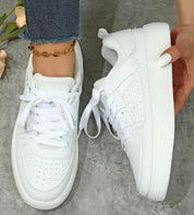 Scarpe da ginnastica bianche da donna, suola spessa, lacci, indossate con jeans. Design moderno, perfette per look casual e sportivi.