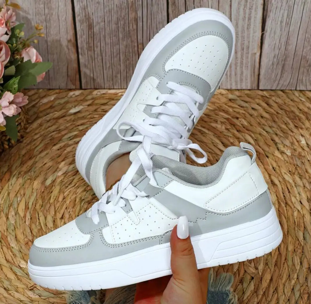 Scarpe da ginnastica bianche e grigie su sfondo di legno, design moderno, suola spessa, perfette per sport e tempo libero. Sneakers moda donna.