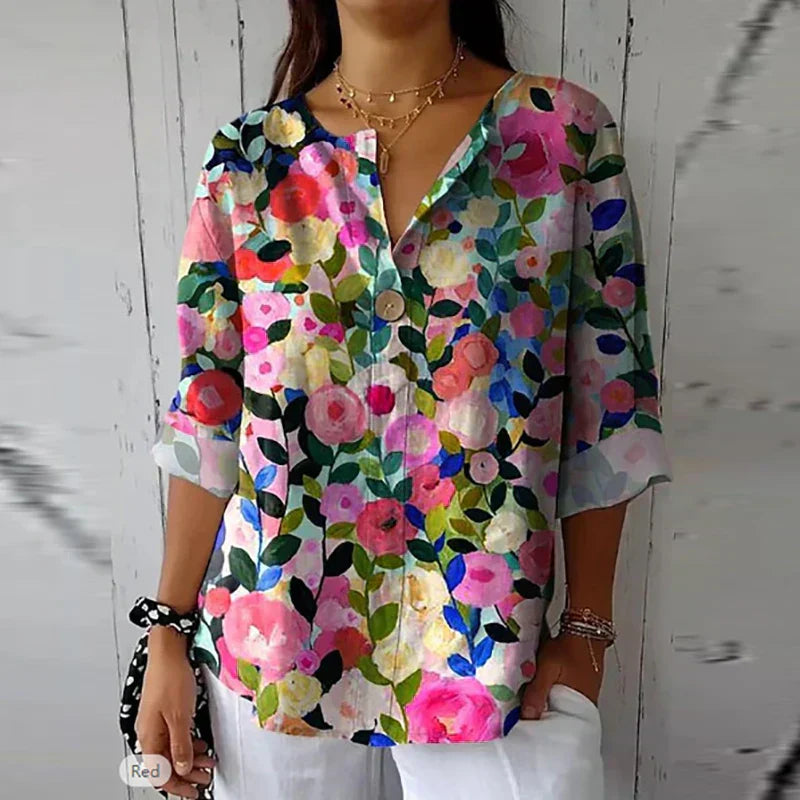 Blusa donna floreale colorata, maniche a tre quarti, scollo a V, sfondo bianco, stile casual elegante, perfetta per primavera estate.