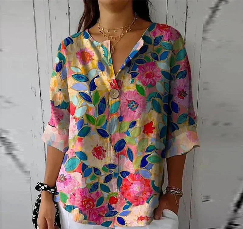 Blusa floreale colorata da donna con scollo a V e maniche a tre quarti, perfetta per la moda estiva. Design vivace e casual su sfondo bianco.
