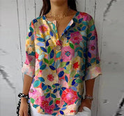 Blusa floreale colorata da donna con scollo a V e maniche a tre quarti, perfetta per la moda estiva. Design vivace e casual su sfondo bianco.