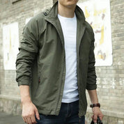 Giacca verde militare da uomo, stile casual, con zip, indossata su maglietta bianca. Ideale per moda urbana e abbigliamento autunnale.