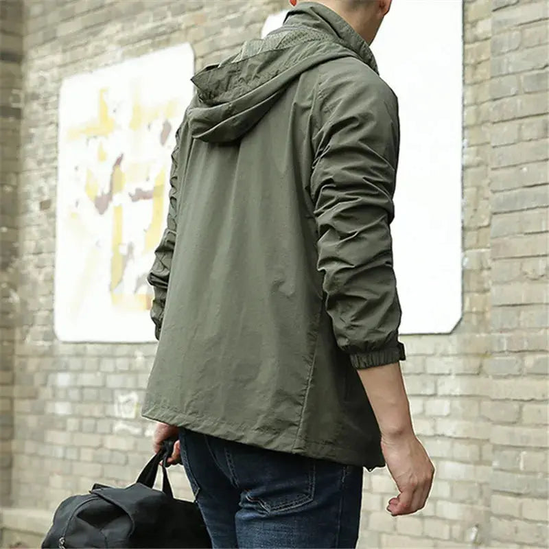 Giacca verde militare uomo, casual, con cappuccio, indossata all'aperto. Moda maschile autunnale, stile urbano, tessuto leggero.