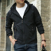 Giacca a vento nera da uomo, casual, con zip, indossata su maglietta bianca. Ideale per moda autunnale, stile urbano.