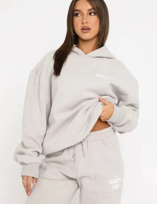 Donna con felpa oversize grigia e pantaloni coordinati, moda casual autunno, abbigliamento comodo, stile streetwear, tendenza 2023.