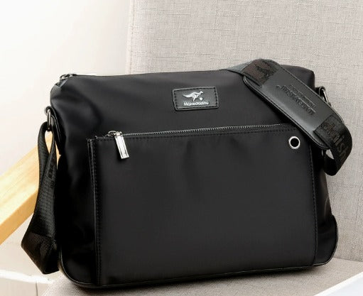 Borsa a tracolla nera in nylon impermeabile, con tasca frontale con zip e tracolla regolabile. Design elegante e pratico per uso quotidiano.