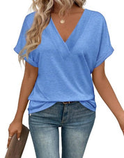 Donna con maglietta blu a V, jeans aderenti, borsa marrone. Moda casual estiva, abbigliamento femminile trendy, look quotidiano elegante.