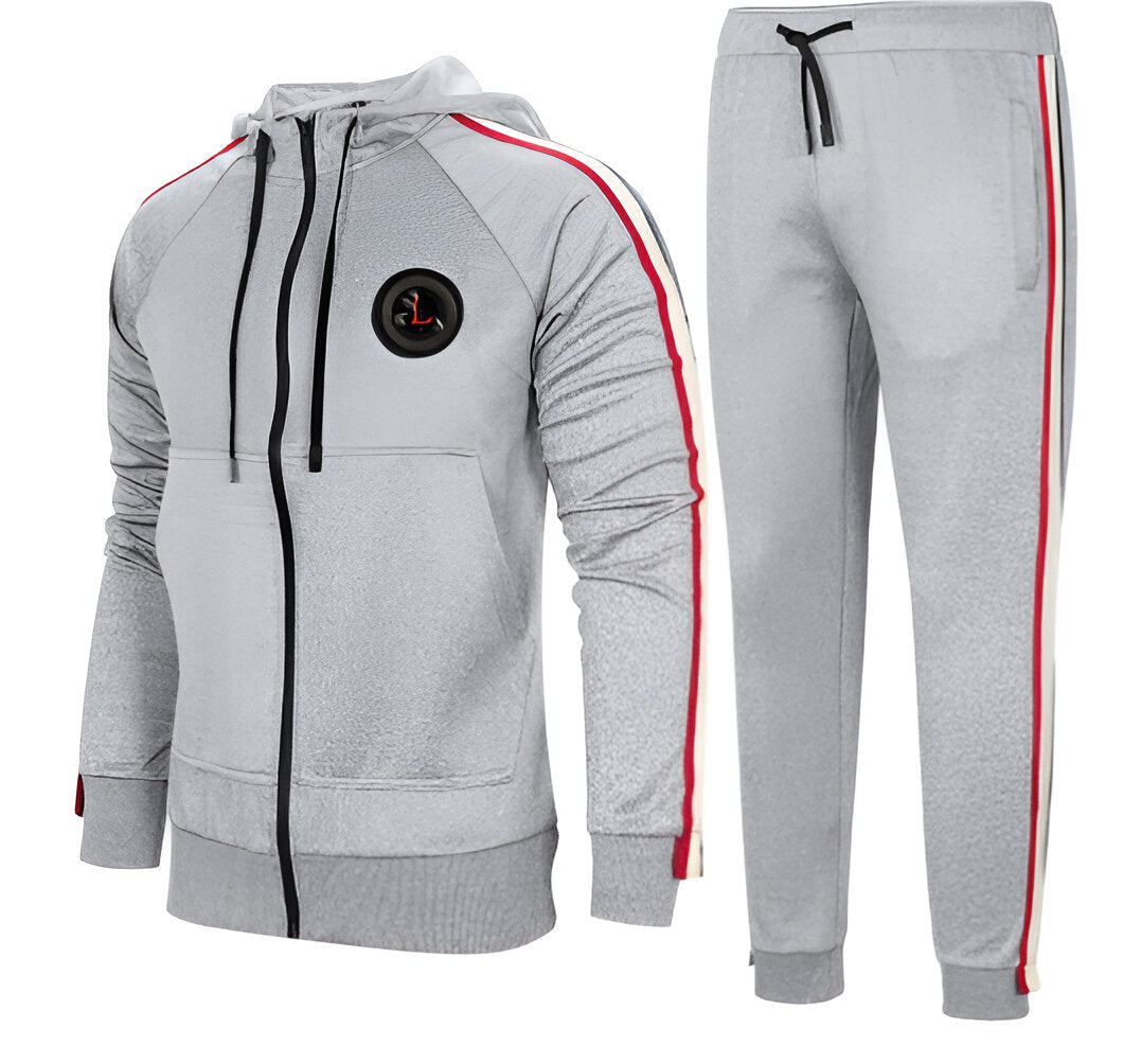 Tuta sportiva grigia da uomo con cappuccio, dettagli a righe rosse e nere, chiusura a zip, pantaloni abbinati. Abbigliamento casual e confortevole.
