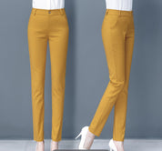 Pantaloni donna giallo senape eleganti, taglio slim fit, vita alta, tasche laterali, chiusura con bottone, abbinati a scarpe bianche con tacco.