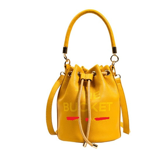 Borsa secchiello gialla in pelle con manico e chiusura a coulisse, design moderno, accessorio moda donna elegante e versatile.