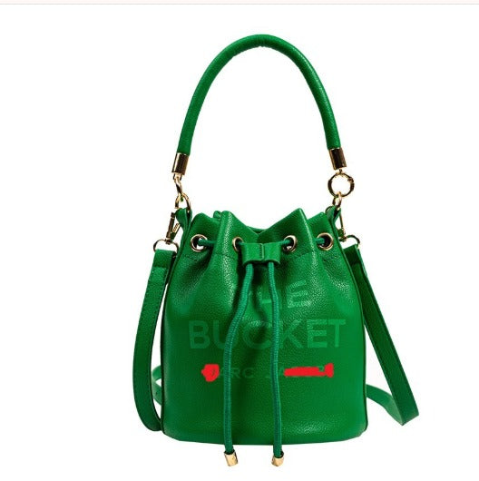 Borsa a secchiello verde in pelle con manico e tracolla regolabile, dettagli dorati. Elegante accessorio moda donna.