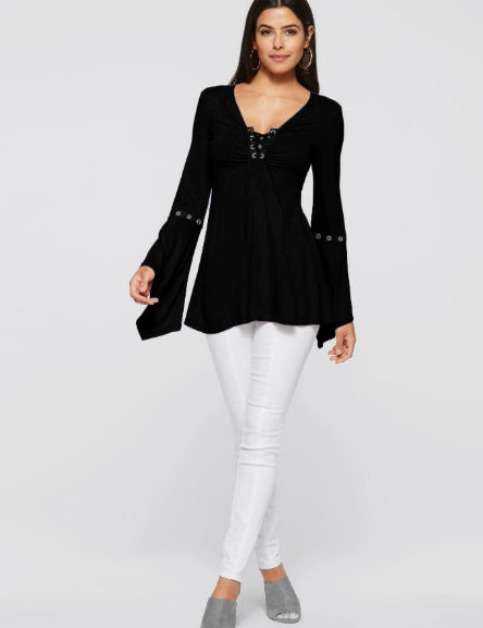 Donna con tunica nera a maniche lunghe e pantaloni bianchi. Moda femminile elegante, abbigliamento casual chic, outfit autunnale.