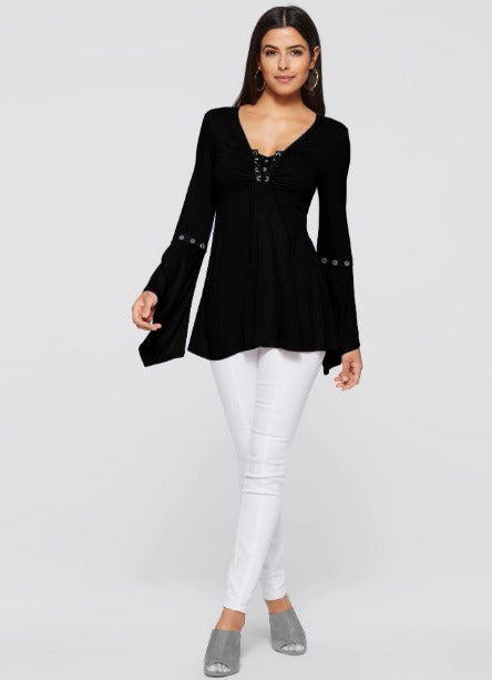 Donna con tunica nera a maniche lunghe e pantaloni bianchi. Moda femminile elegante, abbigliamento casual chic, outfit autunnale.