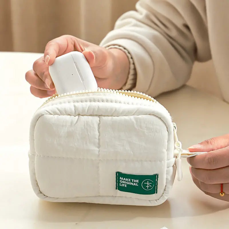 Custodia bianca imbottita con cerniera, ideale per accessori elettronici. Design compatto, tessuto morbido, etichetta verde. Perfetta per viaggi.