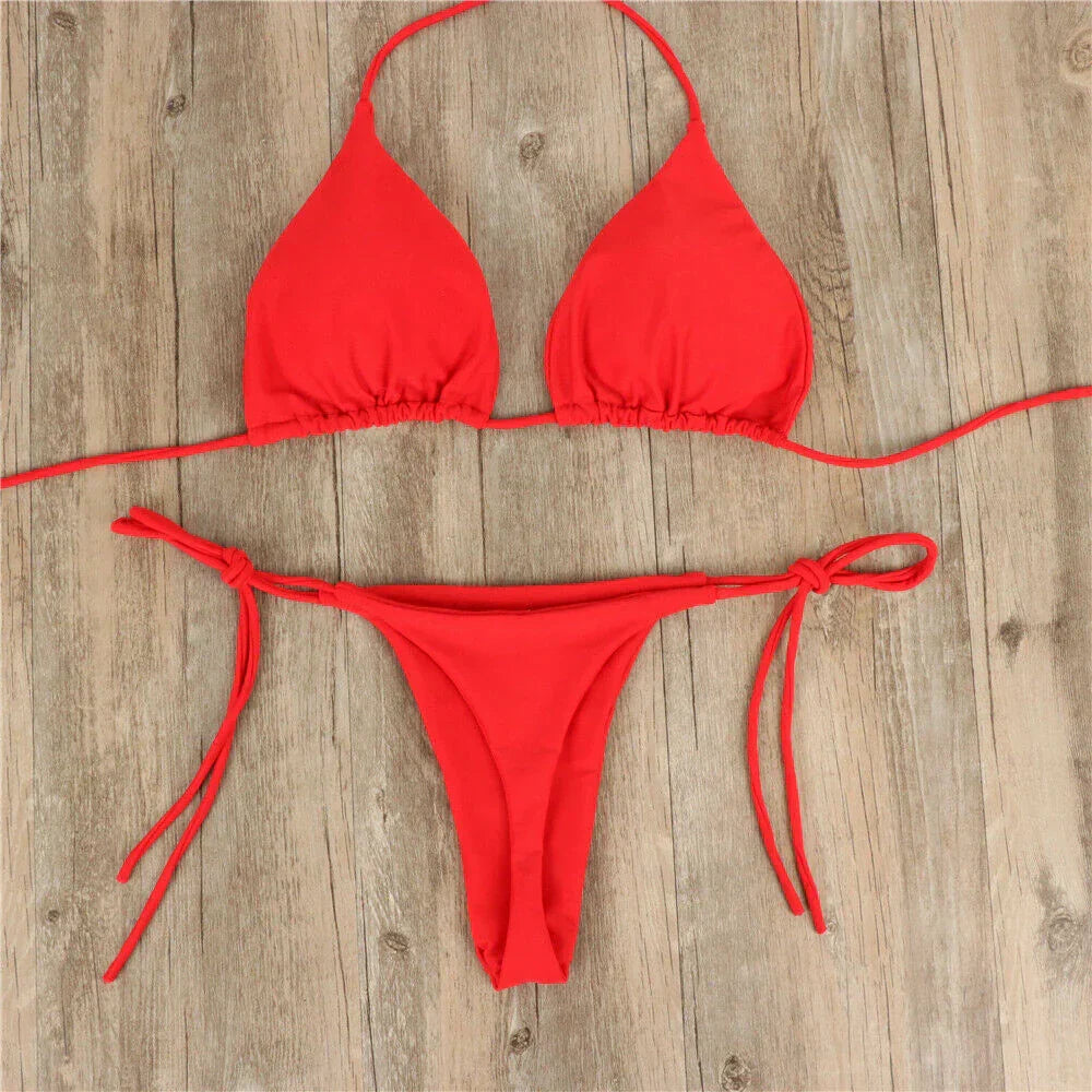 Bikini rosso a due pezzi su sfondo in legno, con top a triangolo e slip con laccetti. Costume da bagno estivo, moda mare donna.
