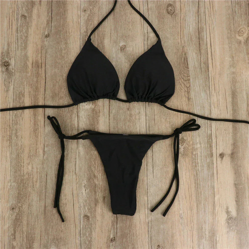Bikini nero a triangolo su pavimento in legno, costume da bagno donna, moda mare, due pezzi, laccetti regolabili, stile estivo elegante.