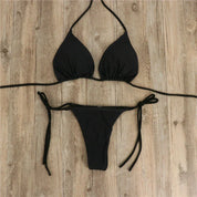 Bikini nero a triangolo su pavimento in legno, costume da bagno donna, moda mare, due pezzi, laccetti regolabili, stile estivo elegante.