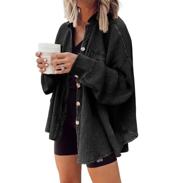 Donna con camicia oversize nera, pantaloncini sportivi e tazza bianca. Moda casual, abbigliamento autunnale, stile urbano.