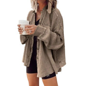 Donna con camicia oversize beige a coste, pantaloncini neri e tazza da caffè. Moda casual autunnale, abbigliamento femminile trendy.