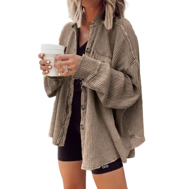 Donna con camicia oversize beige a coste, pantaloncini neri e tazza da caffè. Moda casual autunnale, abbigliamento femminile trendy.