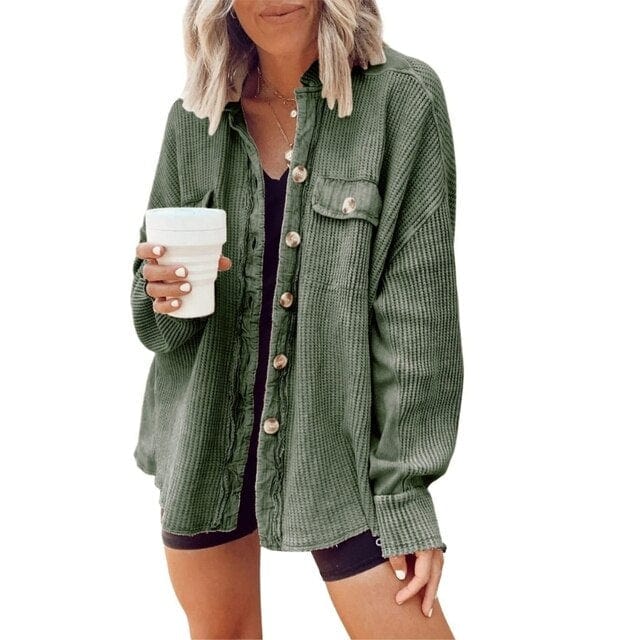 Donna con camicia verde a coste, bottoni in legno, tasca frontale, tiene una tazza bianca. Moda casual autunnale, abbigliamento femminile trendy.