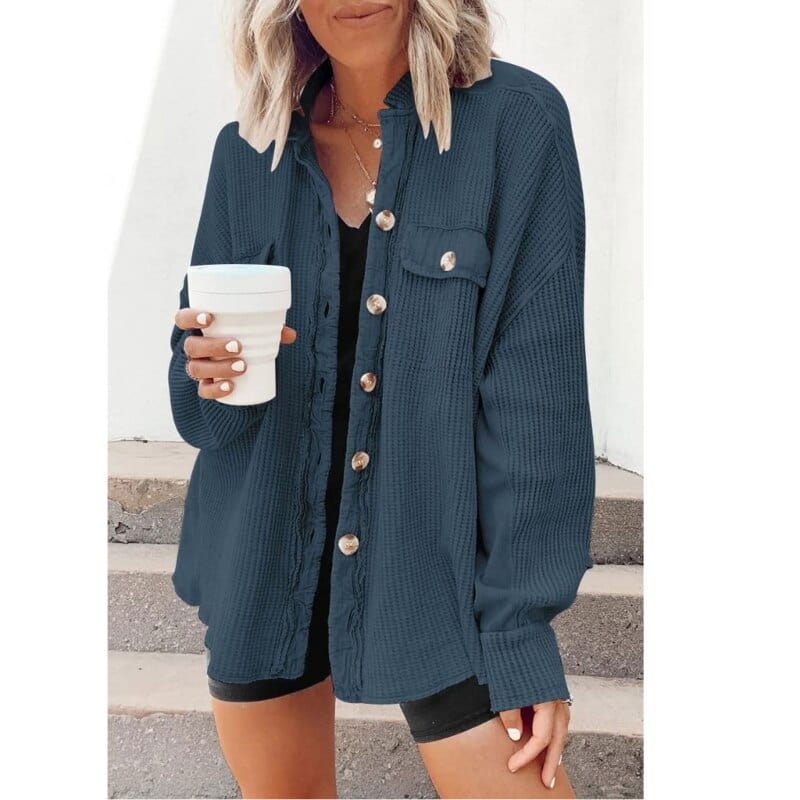 Donna con camicia blu scuro a coste, bottoni dorati, tiene una tazza bianca. Moda casual femminile, abbigliamento autunnale, stile urbano.