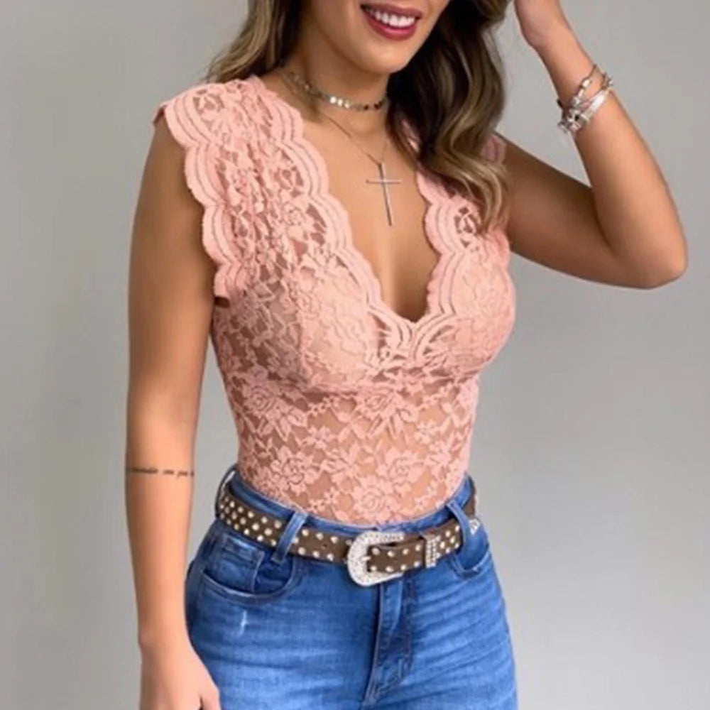 Body in pizzo rosa con scollo a V profondo, indossato con jeans a vita alta e cintura borchiata. Accessori: collana con croce e bracciali.