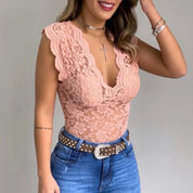 Body in pizzo rosa con scollo a V profondo, indossato con jeans a vita alta e cintura borchiata. Accessori: collana con croce e bracciali.
