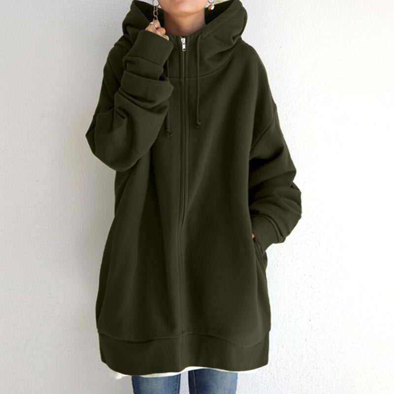 Felpa oversize con cappuccio verde oliva, zip frontale, tasche laterali, indossata con jeans. Moda casual donna, abbigliamento autunnale.