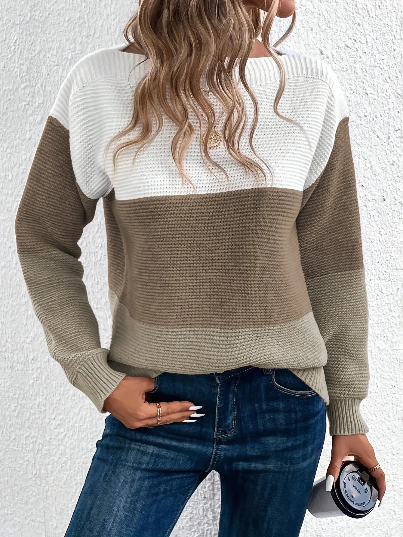 Maglione a righe bianche e marroni, donna con capelli ondulati, jeans blu, tiene una tazza. Moda autunnale casual, abbigliamento femminile trendy.