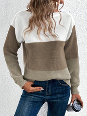 Maglione a righe bianche e marroni, donna con capelli ondulati, jeans blu, tiene una tazza. Moda autunnale casual, abbigliamento femminile trendy.