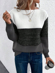 Donna con maglione a righe bianche, nere e grigie, jeans blu, accessori dorati, e tazza da viaggio. Moda casual autunnale, stile moderno.