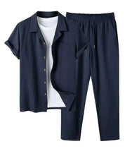 Completo uomo estivo in lino blu scuro, camicia a maniche corte con bottoni e pantaloni elasticizzati, ideale per look casual e freschi.