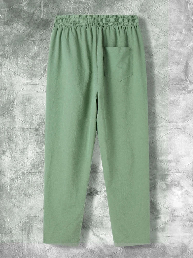 Pantaloni verdi da uomo in cotone, con tasca posteriore, elastico in vita, su sfondo grigio. Ideali per moda casual e comfort quotidiano.