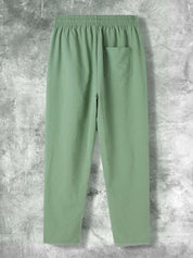 Pantaloni verdi da uomo in cotone, con tasca posteriore, elastico in vita, su sfondo grigio. Ideali per moda casual e comfort quotidiano.