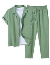 Completo estivo uomo verde salvia, camicia a maniche corte con bottoni e pantaloni elastici, abbinato a t-shirt bianca. Moda casual elegante.
