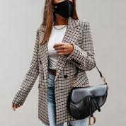 Donna con blazer a quadri, jeans e borsa a tracolla nera. Indossa mascherina nera e maglietta bianca. Moda autunnale elegante e casual.