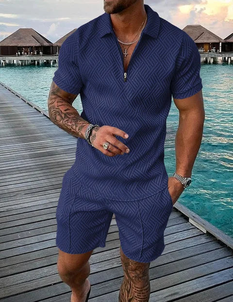 Uomo in completo estivo blu a motivi geometrici, su passerella di legno vicino al mare. Moda maschile, abbigliamento casual, vacanza estiva.
