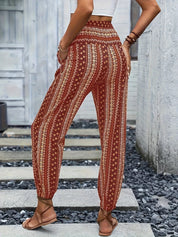 Pantaloni boho a vita alta con stampa etnica, donna di spalle, top bianco, sandali marroni, moda estiva casual, stile bohemien.