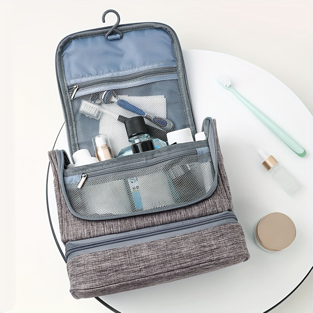 Beauty case da viaggio grigio aperto con gancio, scomparti a rete, contenente articoli da toeletta come spazzolino, flaconi e rasoio.
