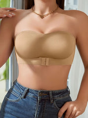Donna indossa reggiseno senza spalline color nude, abbinato a jeans a vita alta. Design elegante, perfetto per abiti scollati. Accessorio moda femminile.