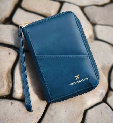 Portafoglio in pelle blu con cerniera, marchio "Forever Myin", su sfondo di pietre. Accessorio elegante e funzionale per viaggi e uso quotidiano.