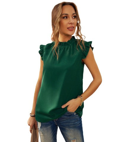 Donna con top verde smeraldo senza maniche, volant sulle spalle, abbinato a jeans. Moda casual elegante, abbigliamento femminile trendy.