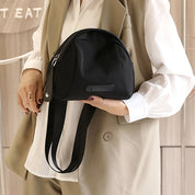 Donna con borsa a tracolla nera elegante, design moderno, abbigliamento casual chic, sfondo neutro. Accessorio moda femminile versatile.