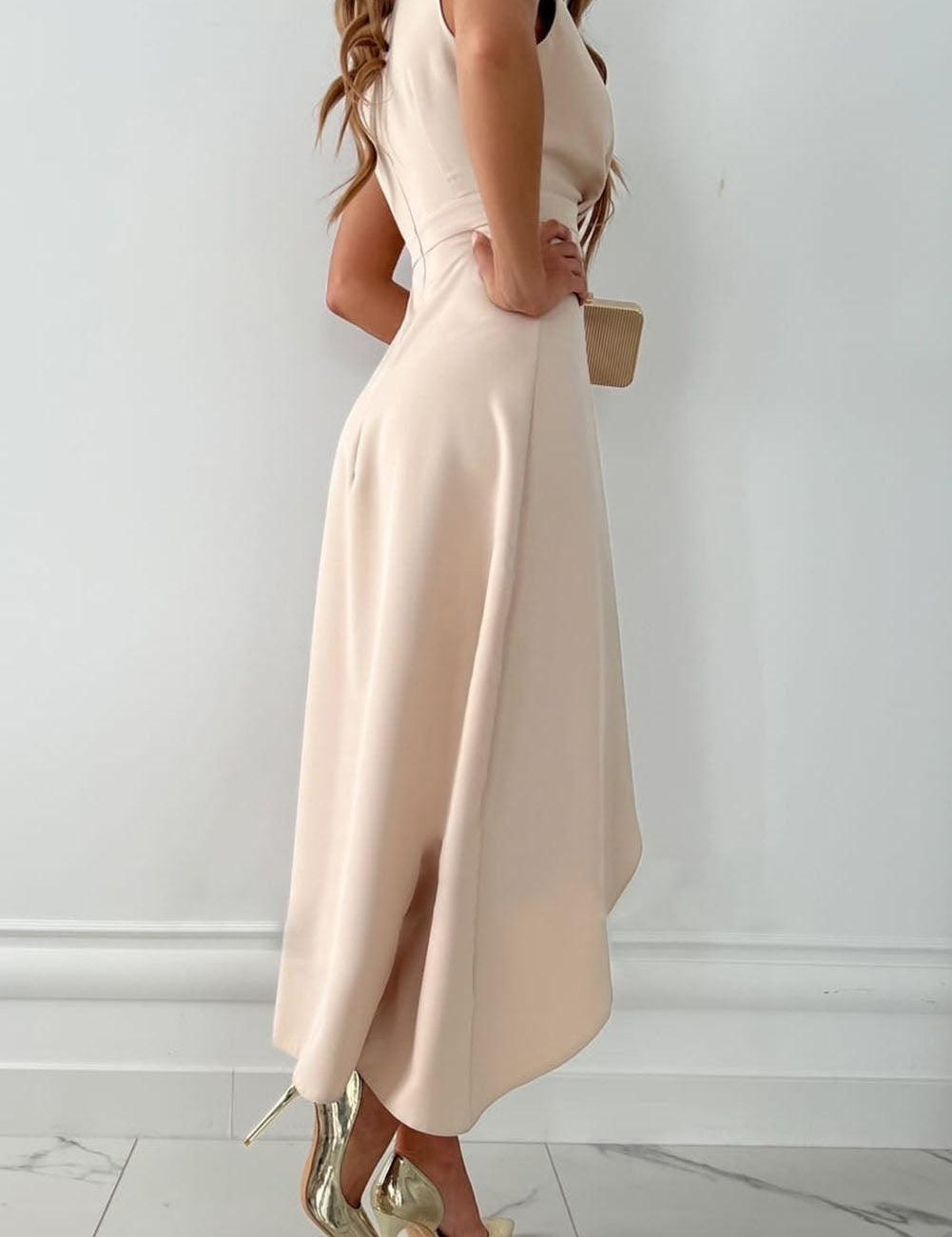 Abito elegante donna color crema, lunghezza midi, senza maniche, con spacco laterale. Scarpe col tacco dorate. Moda femminile chic.
