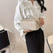 Donna con camicia bianca elegante tiene una borsa beige rettangolare. Moda femminile, accessori chic, stile sofisticato.